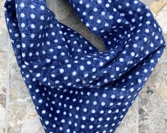 May include: A blue bandana with white polka dots. The bandana is folded and lying on a stone surface.
