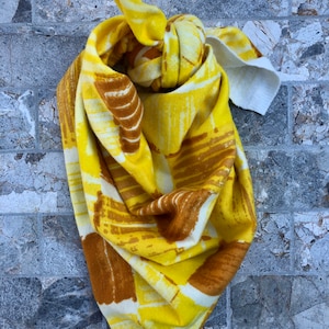 May include: A yellow and brown patterned bandana with a white background. The bandana is tied in a knot.