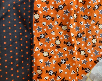 Puede incluir: Dos muestras de tela, una negra con lunares naranjas y la otra naranja con estrellas blancas, maíz dulce y bastones de caramelo.