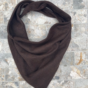 May include: A brown herringbone patterned scarf. The scarf is folded in a triangle shape.