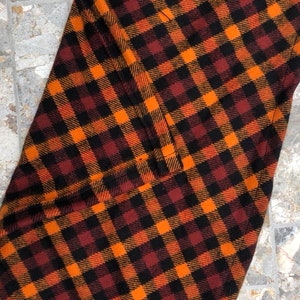 May include: Orange, black, and brown plaid fabric with a sewn seam.