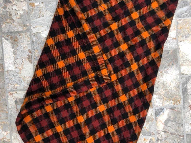 May include: Orange, black, and brown plaid fabric with a sewn seam.