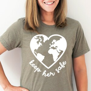 May include: A green t-shirt with a white heart-shaped graphic of the Earth and the text "keep her safe".