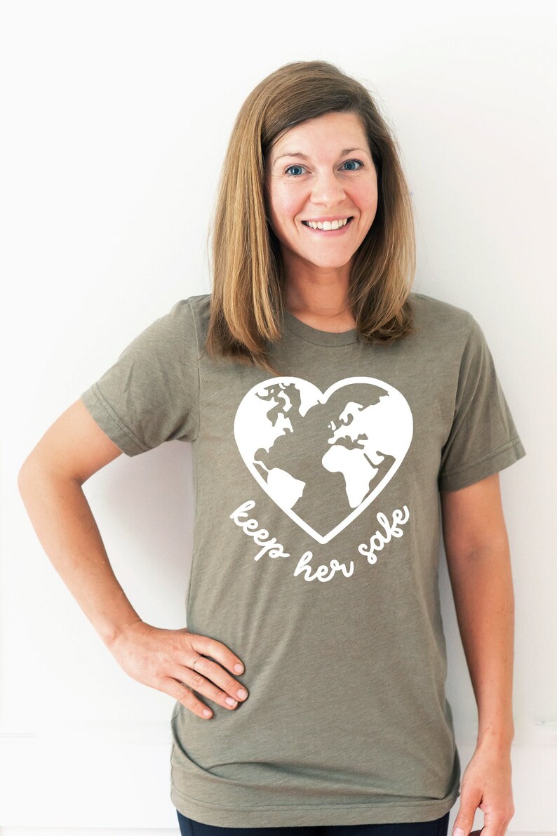 May include: A green t-shirt with a white heart-shaped graphic of the Earth and the text "keep her safe".
