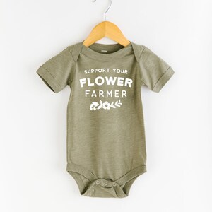 May include: A green baby onesie with white text that reads "Support Your Flower Farmer" with a small floral design below the text.