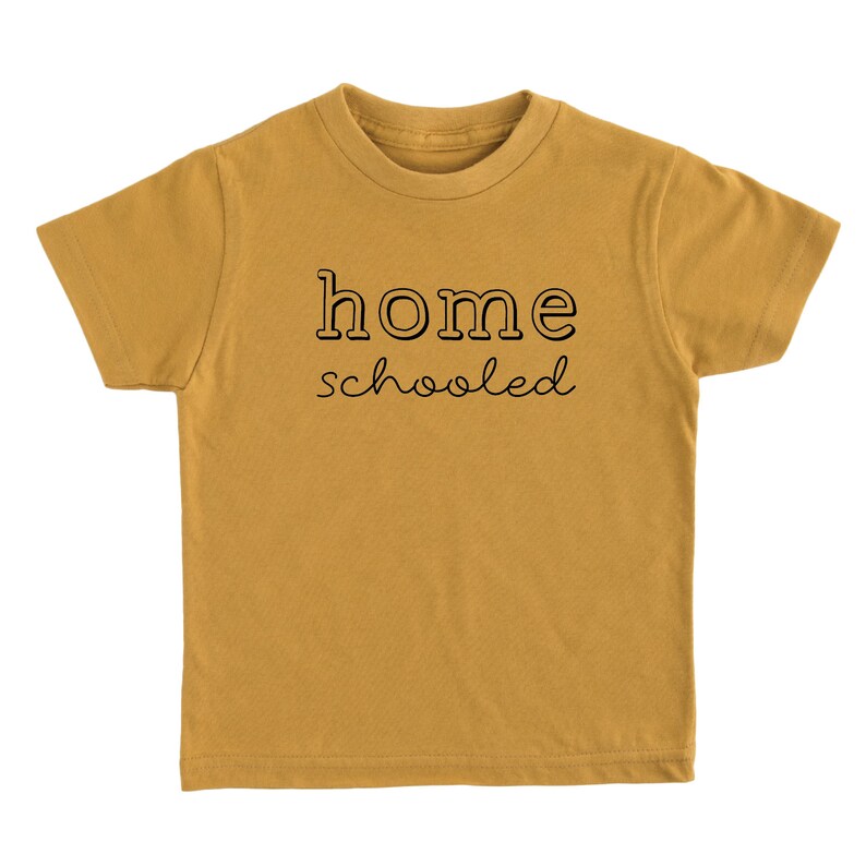 May include: A mustard yellow short-sleeved t-shirt with the text "home schooled" printed in black.
