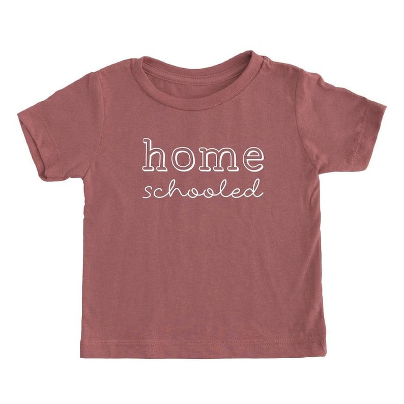 May include: A maroon short-sleeved t-shirt with the text "home schooled" in white.