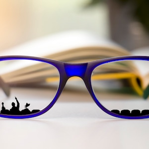 May include: Blue framed eyeglasses with a book in the background. The reflection in the glasses shows a silhouette of a group of people in a stadium.