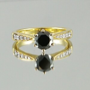 May include: A gold ring featuring a black diamond centre stone and smaller diamonds set in the band.