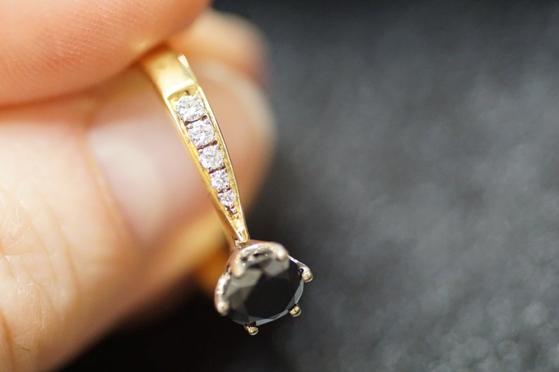 May include: A gold ring featuring a black gemstone and a line of small clear gemstones.