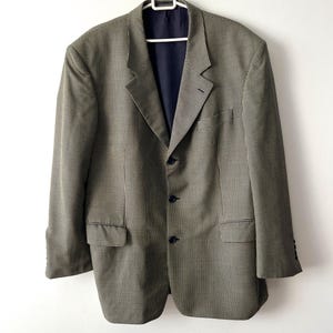 Può includere: Un blazer marrone e nero a quadri con fodera nera e tre bottoni.