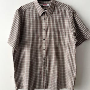 May include: A brown and white plaid short-sleeved button-down shirt with a red "Redhorn" label on the collar.