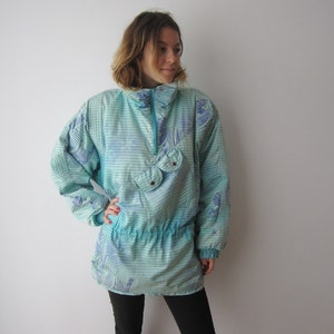 May include: A light blue and purple patterned jacket with a zipper and a drawstring waist.
