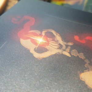 May include: A close-up of a skull with a red and orange glow emanating from its eye sockets. The skull is surrounded by a red and orange smoke-like effect.