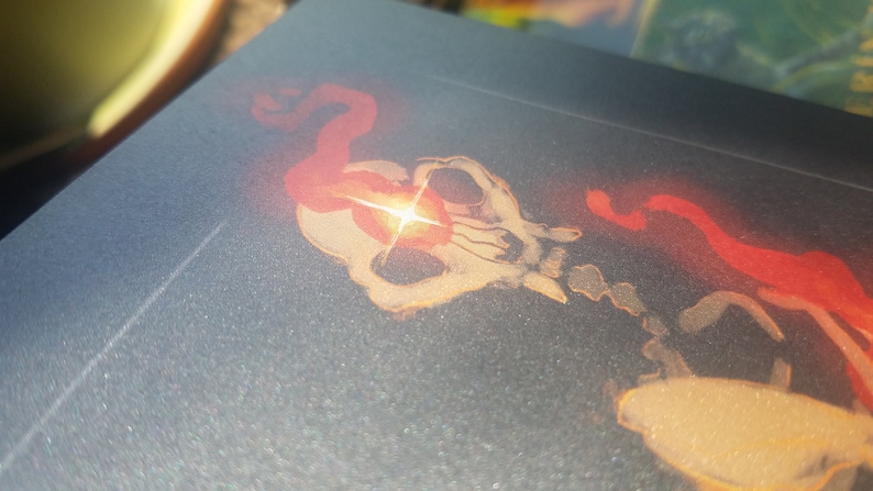 May include: A close-up of a skull with a red and orange glow emanating from its eye sockets. The skull is surrounded by a red and orange smoke-like effect.