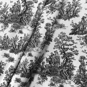 May include: White fabric with a black toile de Jouy pattern. The design features detailed illustrations of people in a pastoral setting, including figures, trees, and animals. The fabric is folded, showing the texture and drape of the material.