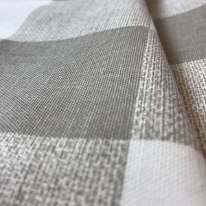 May include: A fabric featuring a large-scale buffalo check pattern in alternating squares of solid light gray and a textured, mottled blend of white and gray. The material has a visible woven structure with a distinct, tactile surface grain.