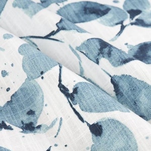 May include: White fabric with a blue watercolor leaf pattern. The leaves are abstract and have a splattered effect.