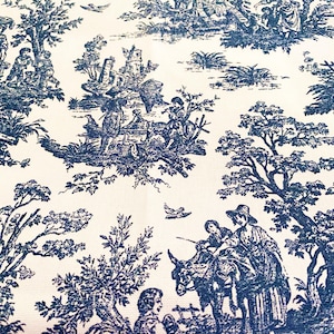 May include: Cream-colored fabric with a repeating blue toile pattern. The design depicts pastoral scenes with figures, trees, and buildings. The overall aesthetic is reminiscent of classic French country decor.