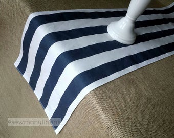 May include: A white and navy blue striped table runner. The runner is made of fabric and has a simple design. It is shown on a hessian surface.