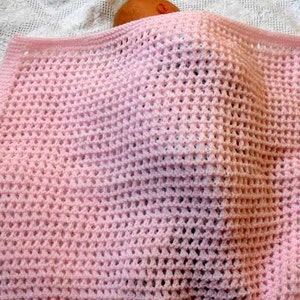 May include: A pink crocheted baby blanket with a delicate open-stitch pattern.