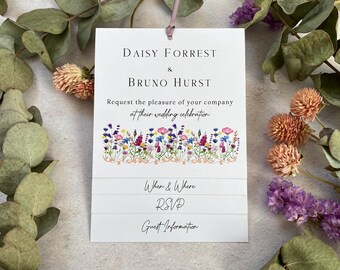 Puede incluir: Una invitación de boda blanca con un diseño floral con una variedad de flores coloridas. La invitación dice "Daisy Forrest & Bruno Hurst Les solicitan el placer de su compañía en su celebración de boda When & Where RSVP Guest Information"