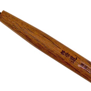 以下が含まれることがあります： 黒い金属の先端が付いた木製の柄の彫刻ツール。柄は明るい茶色で、木目が見えます。柄には文字が印刷されています。このツールは、詳細な彫刻作業用に設計されています。