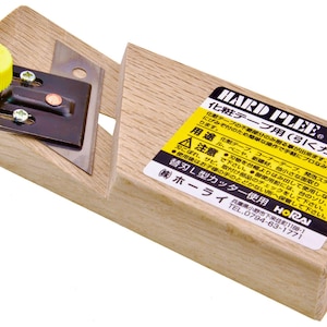 May include: A wooden corner tape tool with a metal blade and a yellow adjustment knob. The tool has a black metal plate with screws and Japanese text on a yellow label.