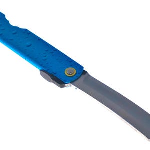 Könnte beinhalten: Ein Klappmesser mit einem leuchtend blauen Griff, der eine texturierte Oberfläche mit Wassertropfen aufweist. Das Messer hat eine metallisch silberne Klinge mit einer scharfen, abgewinkelten Spitze und einen gelb-silbernen Drehpunkt.