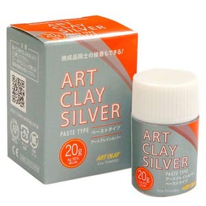 Könnte beinhalten: Silberfarbene Tonpaste in einem kleinen, zylindrischen Behälter mit weißem Deckel, neben einer passenden Schachtel. Auf der Schachtel und dem Behälter steht in großen Buchstaben "ART CLAY SILVER", darunter japanischer Text. Der Behälter enthält 20g Ton.