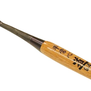 May include: A wood carving gouge with a curved blade. The tool has a wooden handle with Japanese text and a metal ferrule. The blade is made of steel.