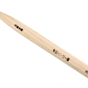 Puede incluir: Una herramienta de madera con una punta de metal fina, etiquetada "1.5mm" y "木刀" en caracteres japoneses. La herramienta se utiliza para tallar y tiene un mango de madera.