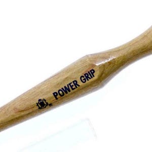 Può includere: Un utensile Power Grip con manico in legno e punta in metallo nero. L'utensile ha una finitura marrone chiaro e le parole "POWER GRIP" sono stampate sul manico. L'utensile è progettato per lavori di precisione.