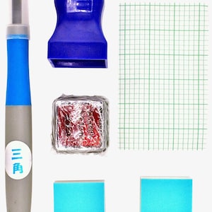 以下が含まれることがあります： 青いインクパッド、赤いインクパッド、青いスポンジ2つ、青いハンドルが付いた灰色のツール、方眼紙のセットです。