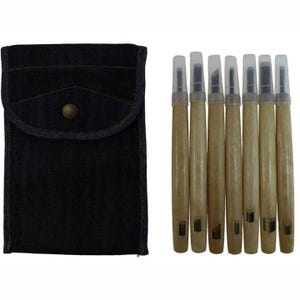 Puede incluir: Un juego de seis herramientas para tallar madera con tapas protectoras de plástico transparente, junto a una funda de mezclilla azul oscuro con cierre de botón a presión. Las herramientas tienen mangos de madera marrón claro y cuchillas de metal.