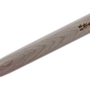 Puede incluir: Un cincel de madera con una hoja de metal negro. El mango es de madera clara con un patrón de veta. El cincel tiene texto japonés en el mango que dice "黒崎  製作所".