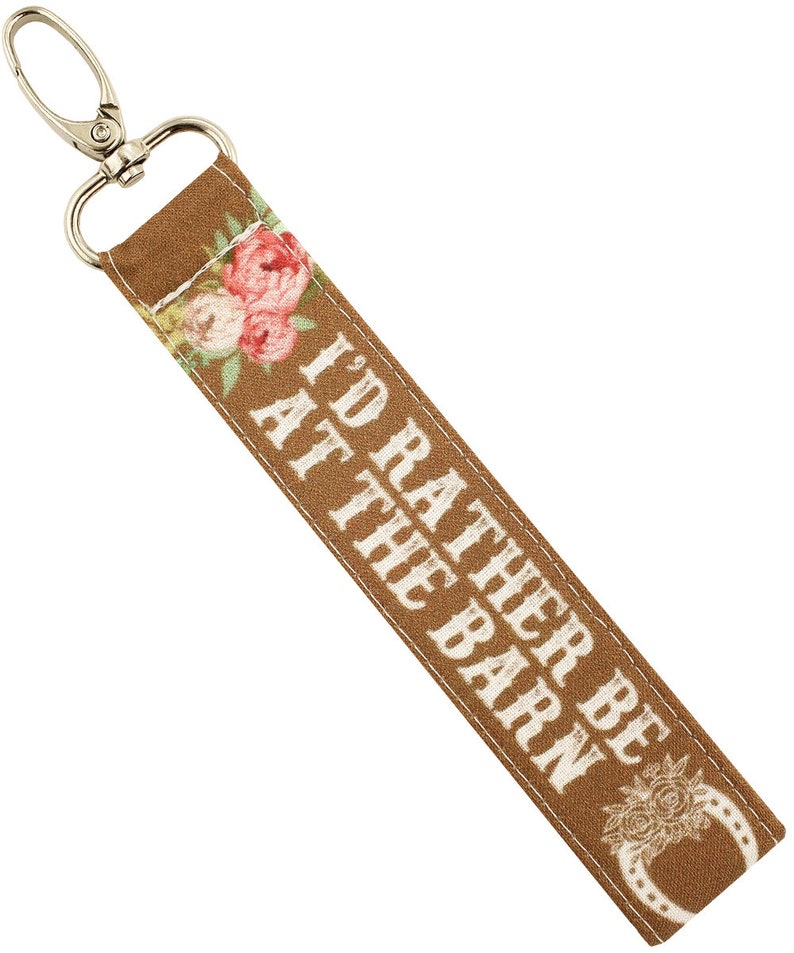 May include: A brown key chain with a floral design and the text "I'd rather be at the barn".