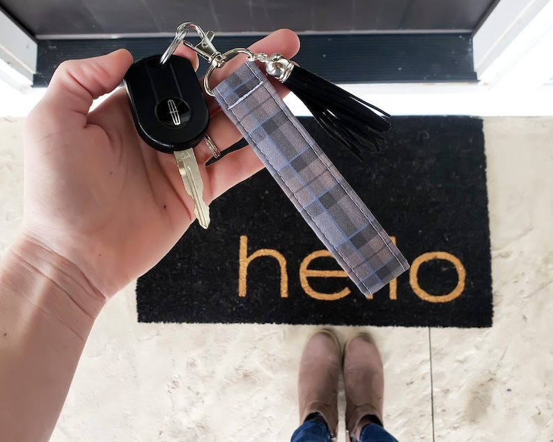 Peut inclure: Un porte-cl&eacute;s en tissu &agrave; carreaux gris et bleus avec un pompon noir. Le porte-cl&eacute;s est attach&eacute; &agrave; un anneau de cl&eacute; argent&eacute; et &agrave; une cl&eacute; de voiture noire.