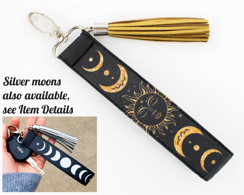 Puede incluir: Llavero negro con un dise&ntilde;o de sol y luna dorado. El llavero tiene un borla dorada y un anillo de llave plateado.  "Silver moons also available, see Item Details" est&aacute; escrito en la imagen.