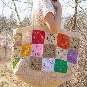 Puede incluir: Una gran bolsa de mano de crochet con un dise&ntilde;o de patchwork. La bolsa est&aacute; hecha de hilo beige con cuadrados coloridos en tonos de verde, rojo, naranja, amarillo, rosa, morado y blanco.