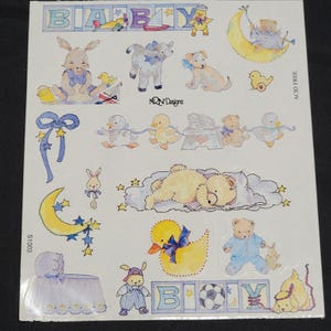 May include: A sheet of baby-themed stickers featuring various illustrations. The stickers include a bunny, lamb, puppy, ducklings, teddy bears, and a sleeping bear. The word "BOY" is spelled out with letter blocks. The stickers are in pastel colors.