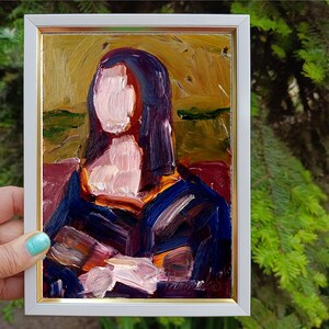 May include: Oil painting of a woman in a white framed gold-trimmed frame. The painting features a woman with dark hair and a blue dress. The painting has a textured brushstroke style with colors of blue, purple, and gold.