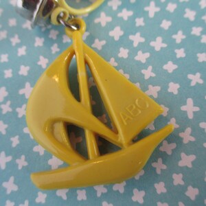 May include: A yellow plastic sailboat keyring with the letters "ABC" on the sail.