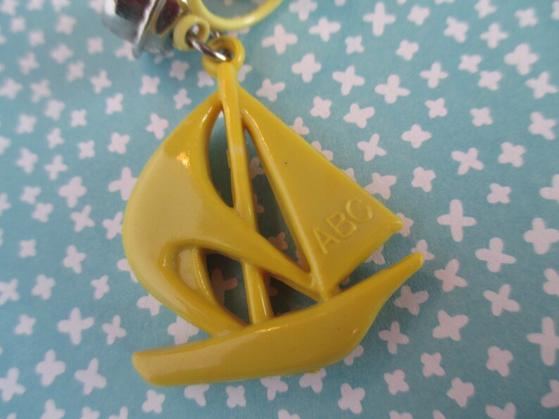 May include: A yellow plastic sailboat keyring with the letters "ABC" on the sail.