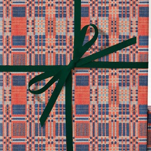 May include: Three gift boxes wrapped in red and blue plaid patterned paper. The top box is tied with a dark green ribbon.