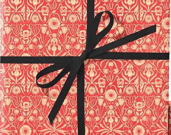 May include: Gift boxes wrapped in red paper with a cream-colored floral pattern. One box is tied with a black ribbon. The boxes are various sizes, suggesting a set of gifts ready for a special occasion.