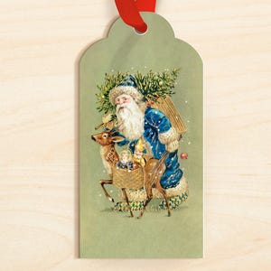 May include: A vintage-style Christmas gift tag featuring Santa Claus in a blue coat, carrying a basket and a fir tree, with a reindeer. The tag has a red ribbon for hanging. The background is a light green color.
