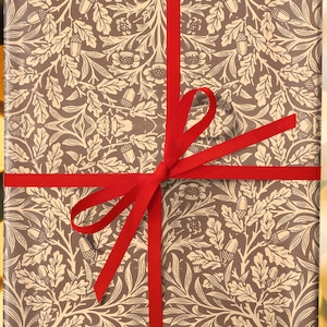 May include: A brown gift box with a cream and gold floral pattern. The box is tied with a red ribbon.