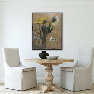 Puede incluir: Pintura abstracta en tonos de marr&oacute;n, verde y blanco con l&iacute;neas negras. La pintura est&aacute; enmarcada en negro y colgada en una pared blanca sobre una mesa de madera con dos sillas.