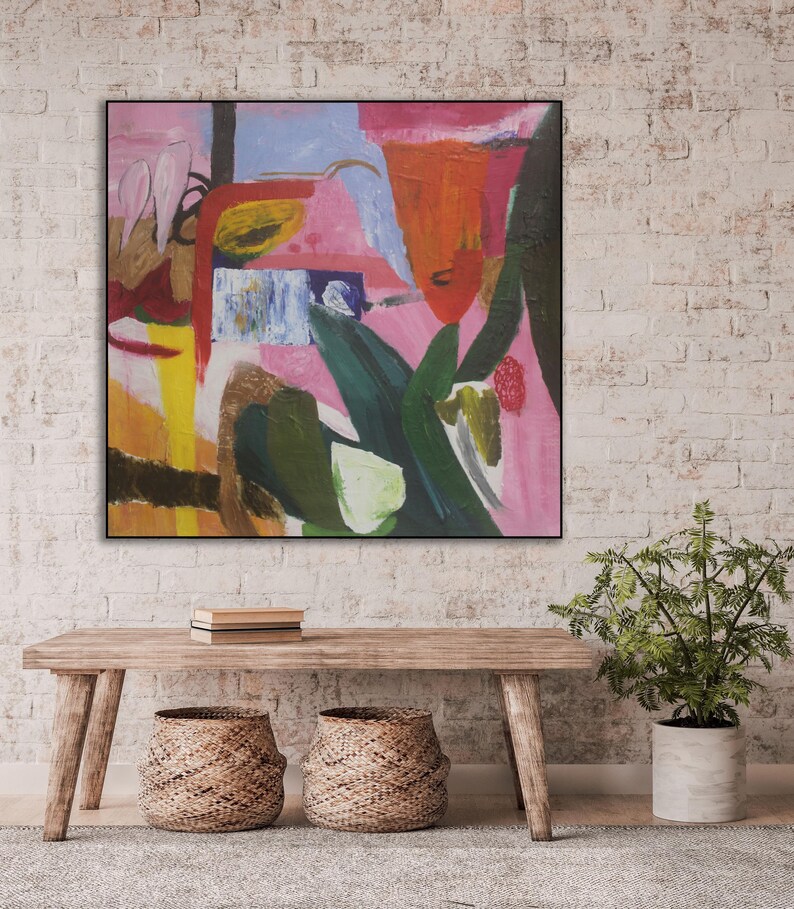 May include: Abstract painting with bold strokes of pink, orange, yellow, green, and blue. The painting is framed in black and hangs on a white brick wall.